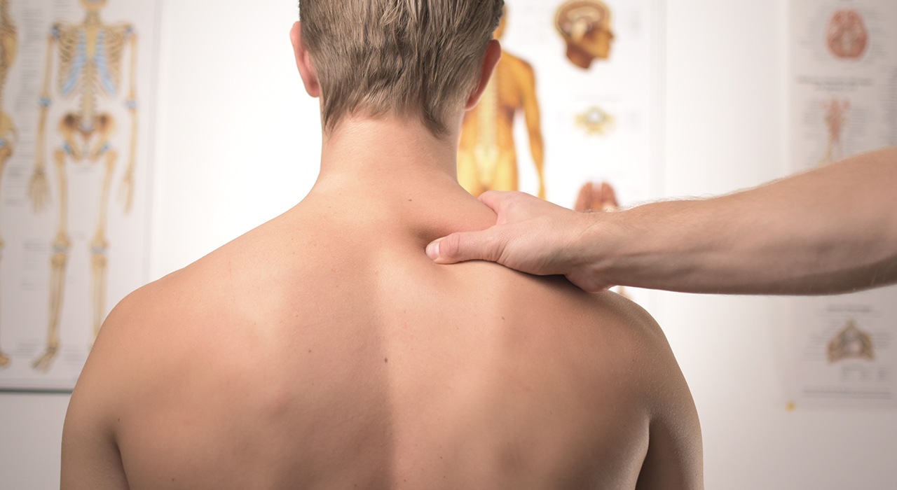 鍼灸師に肩を診てもらう男性